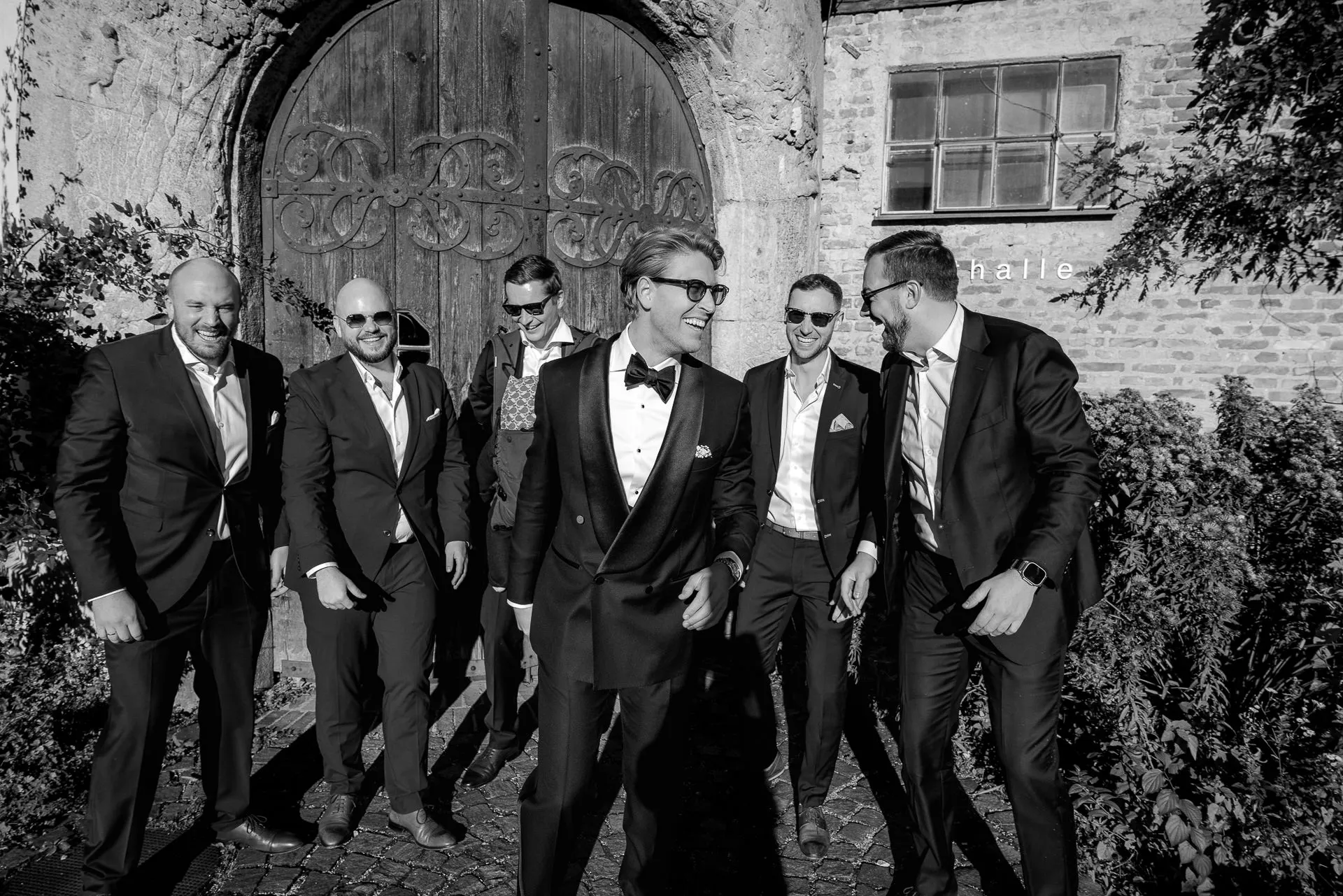 Joyful groomsmen and groom laughing at Gut Sonnenhausen wedding in black and white