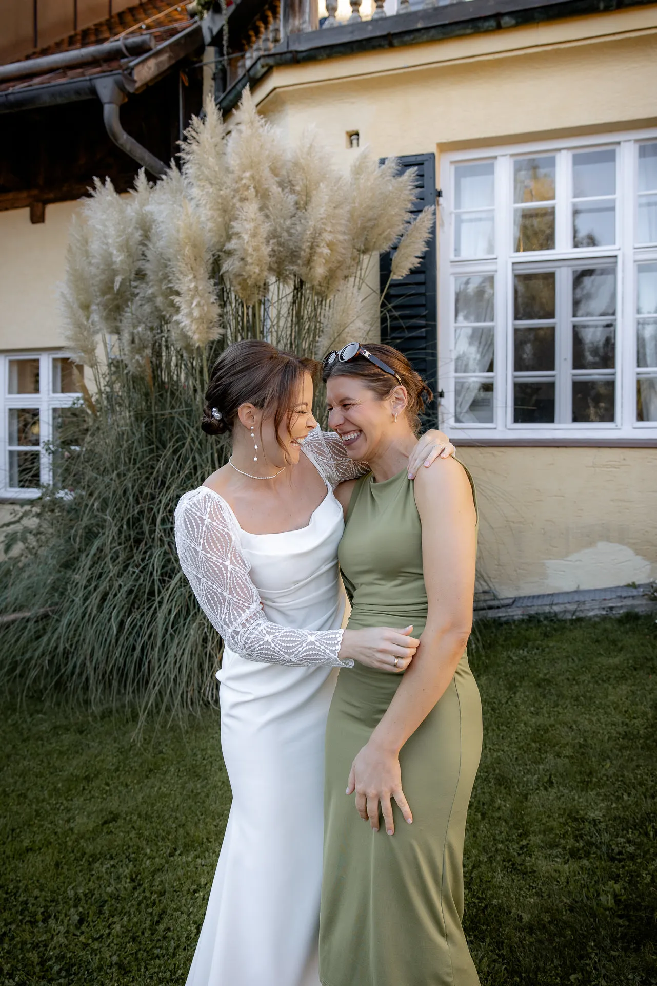 Bride and friend laughing embraced at Gut Sonnenhausen wedding
