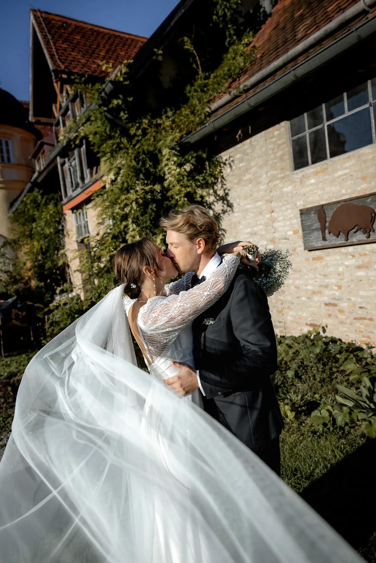 Bride and groom kissing romantically in front of historic building at Gut Sonnenhausen wedding