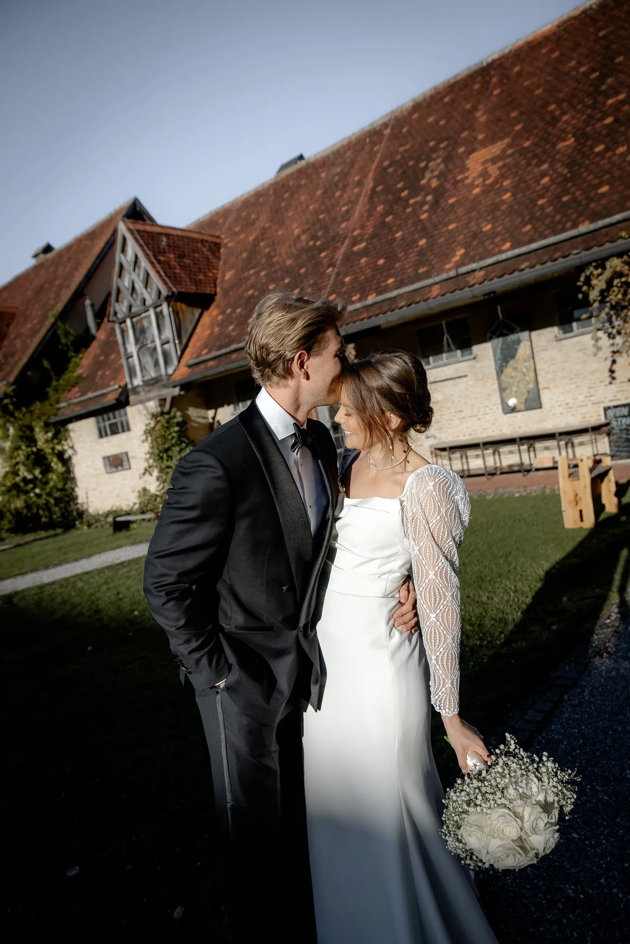 Bride and groom kissing tenderly in front of country estate at Gut Sonnenhausen wedding