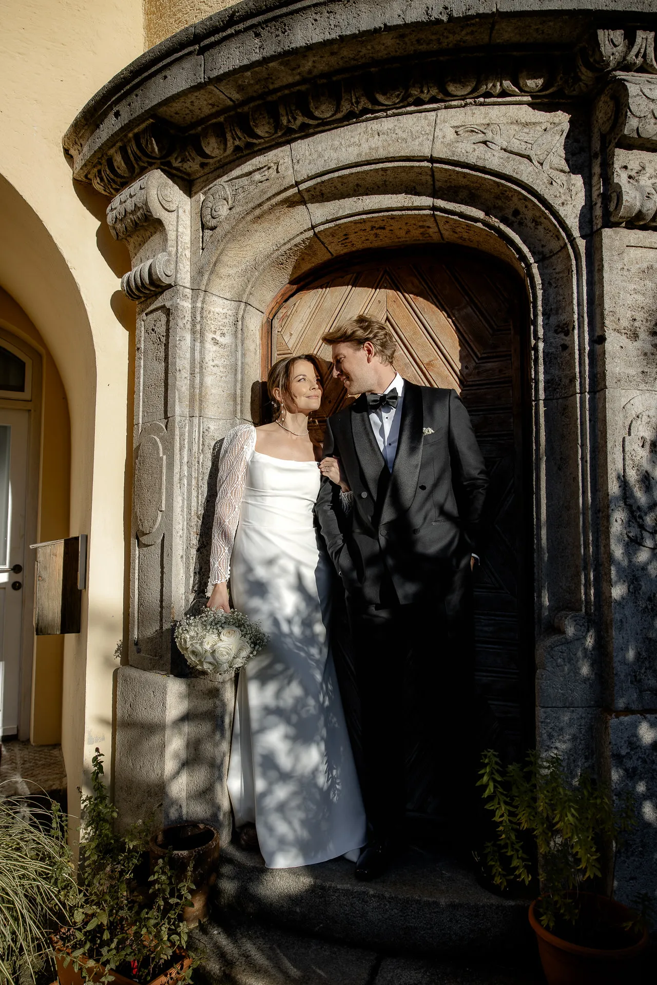Bride and groom posing under stone archway at country wedding at Gut Sonnenhausen