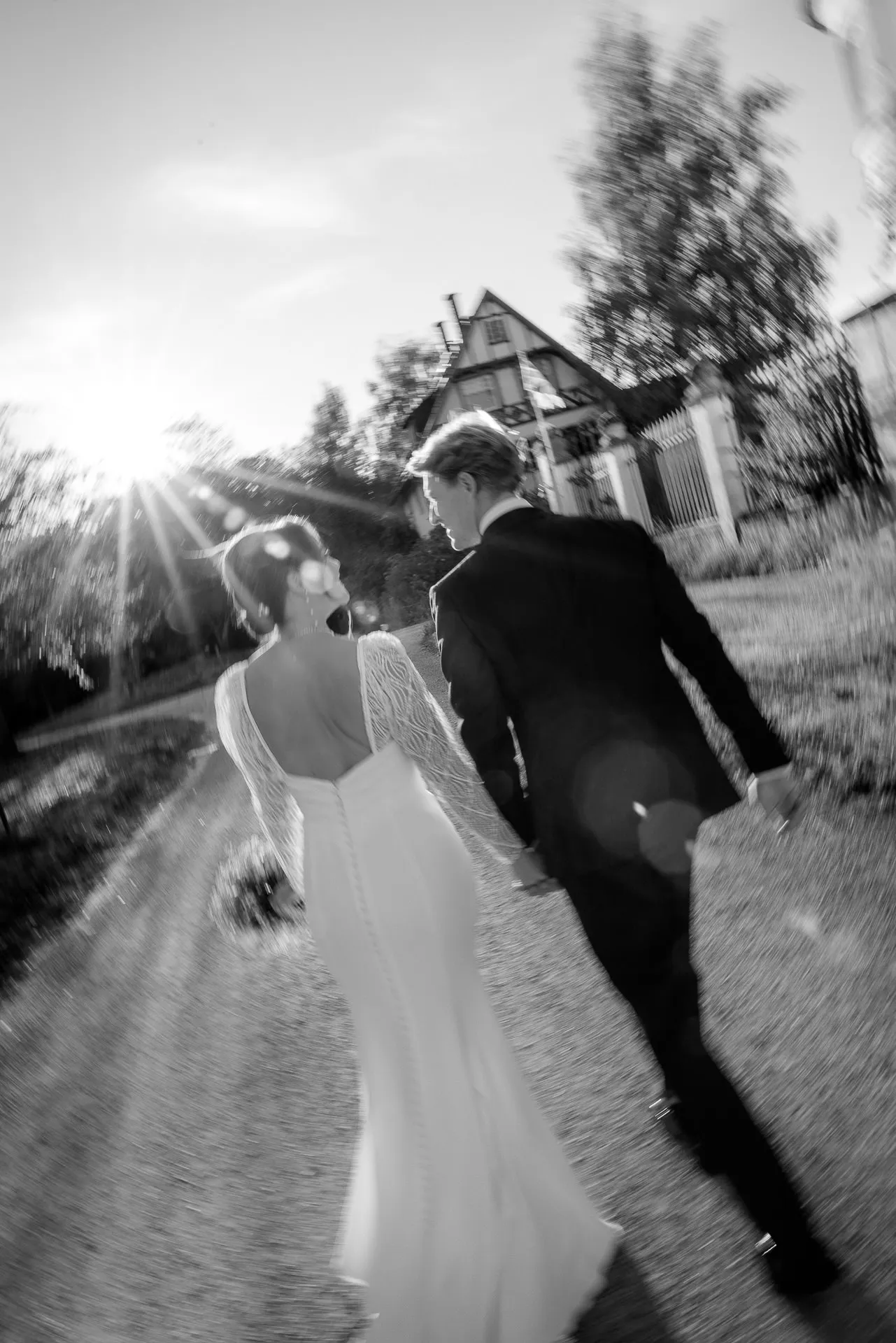 Bride and groom walking hand in hand on path at Gut Sonnenhausen wedding in black and white