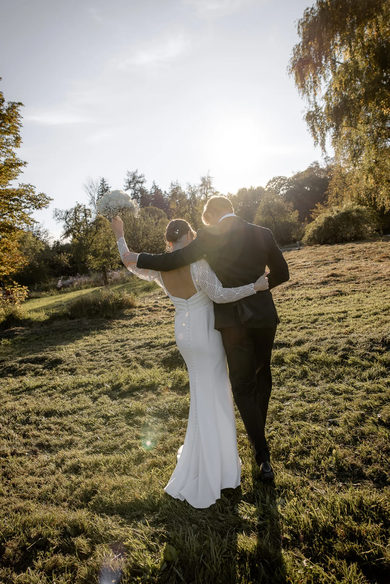 Bride and groom walking through meadow at Gut Sonnenhausen country wedding