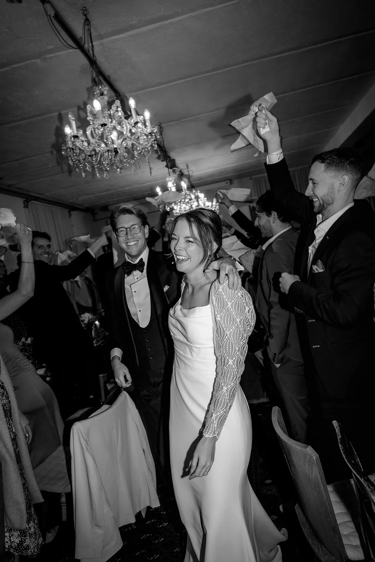 Bride and groom walking through celebrating guests with napkins at Gut Sonnenhausen in black and white
