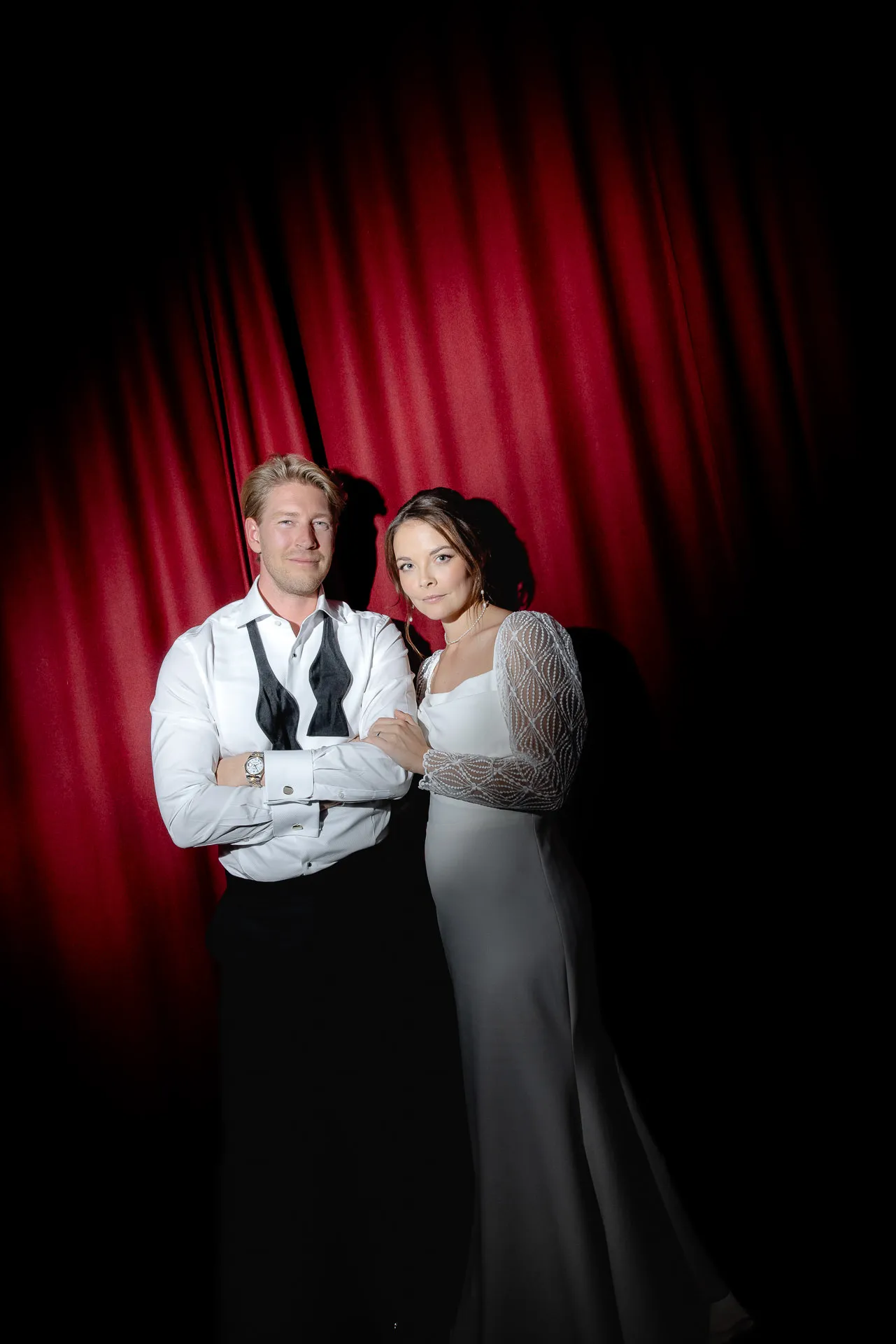 Elegant bride and groom posing in front of red curtain at Gut Sonnenhausen wedding