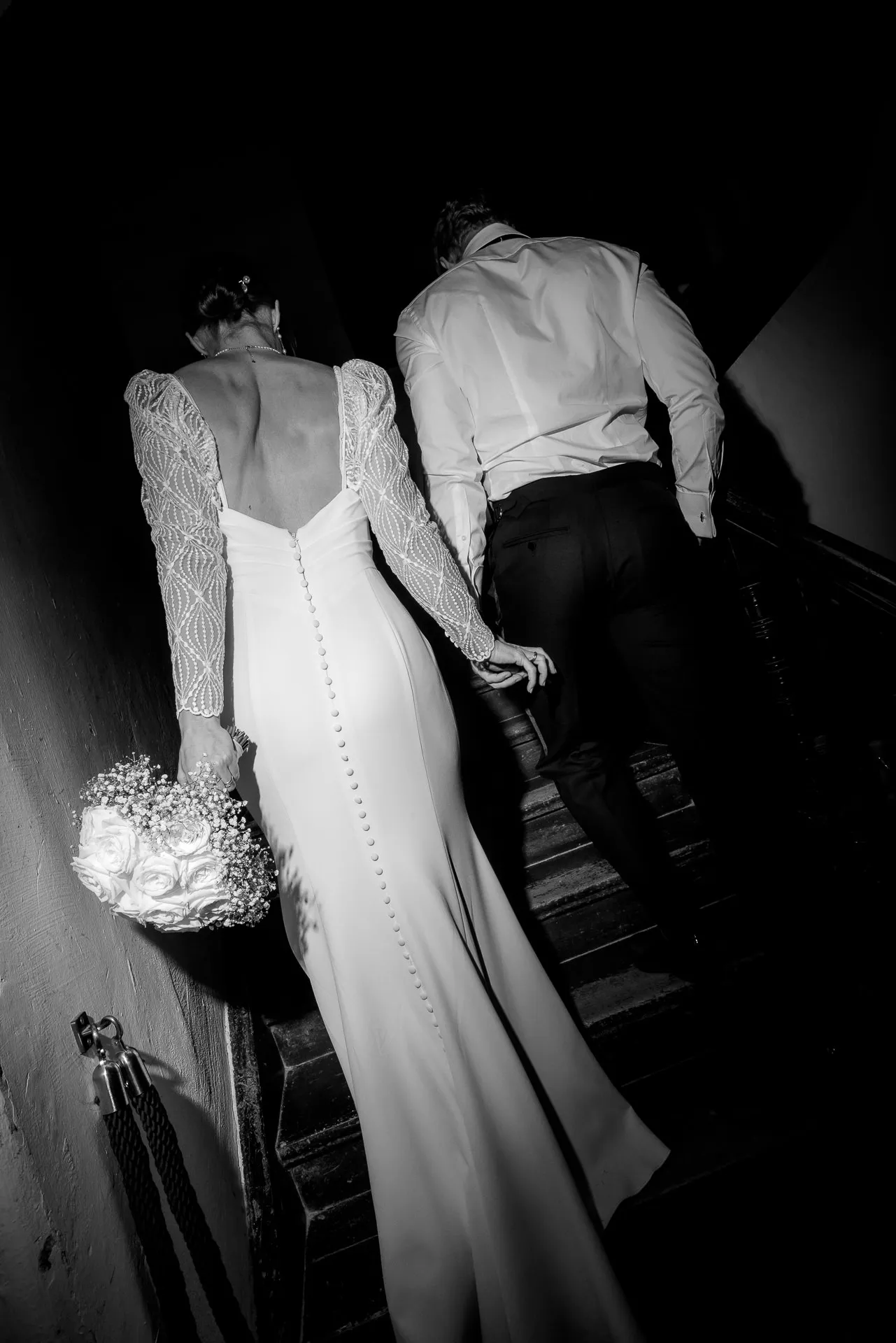 Bride and groom ascending staircase at Gut Sonnenhausen wedding in black and white