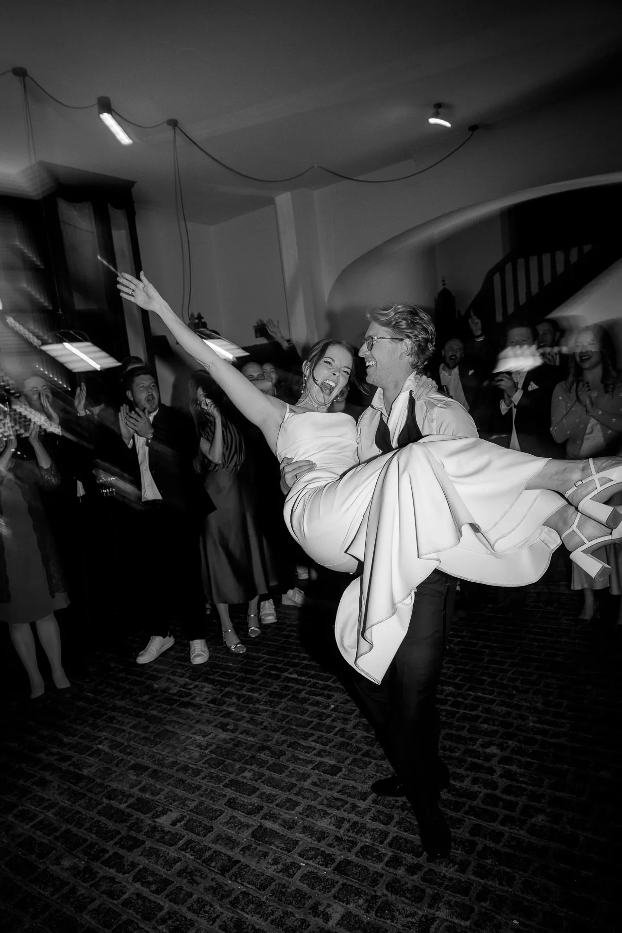 Bride and groom dancing exuberantly at wedding celebration at Gut Sonnenhausen in black and white