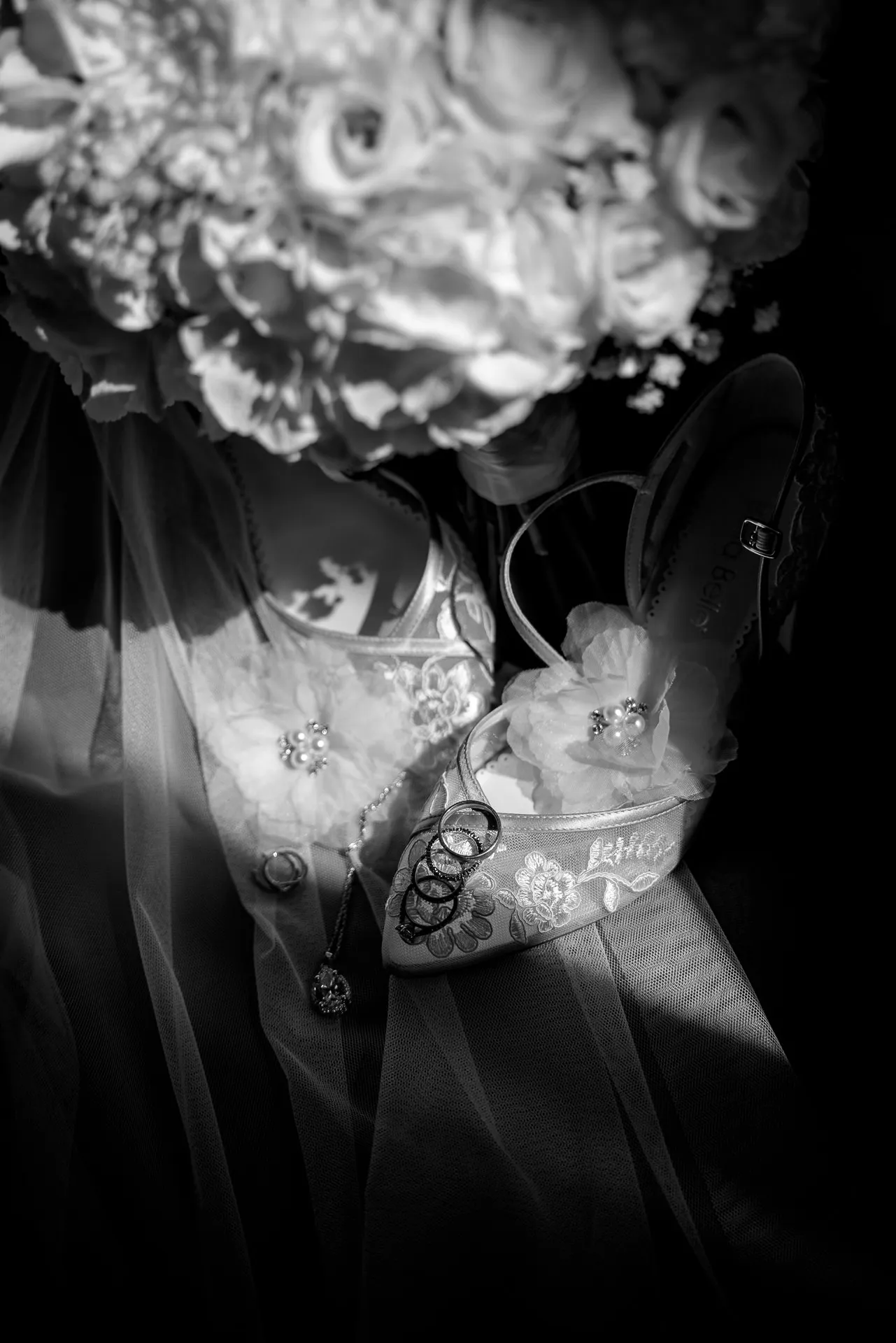 Elegant bridal shoes with wedding rings and bouquet in black and white