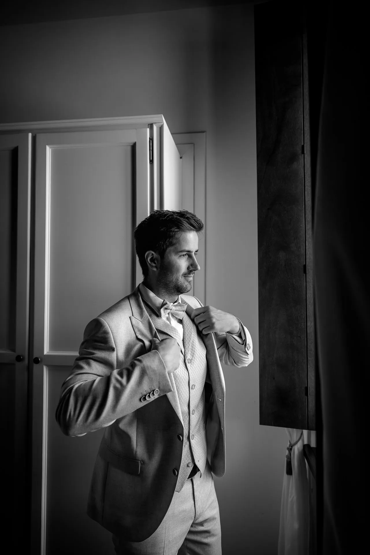 Elegant groom getting ready portrait while adjusting his tie