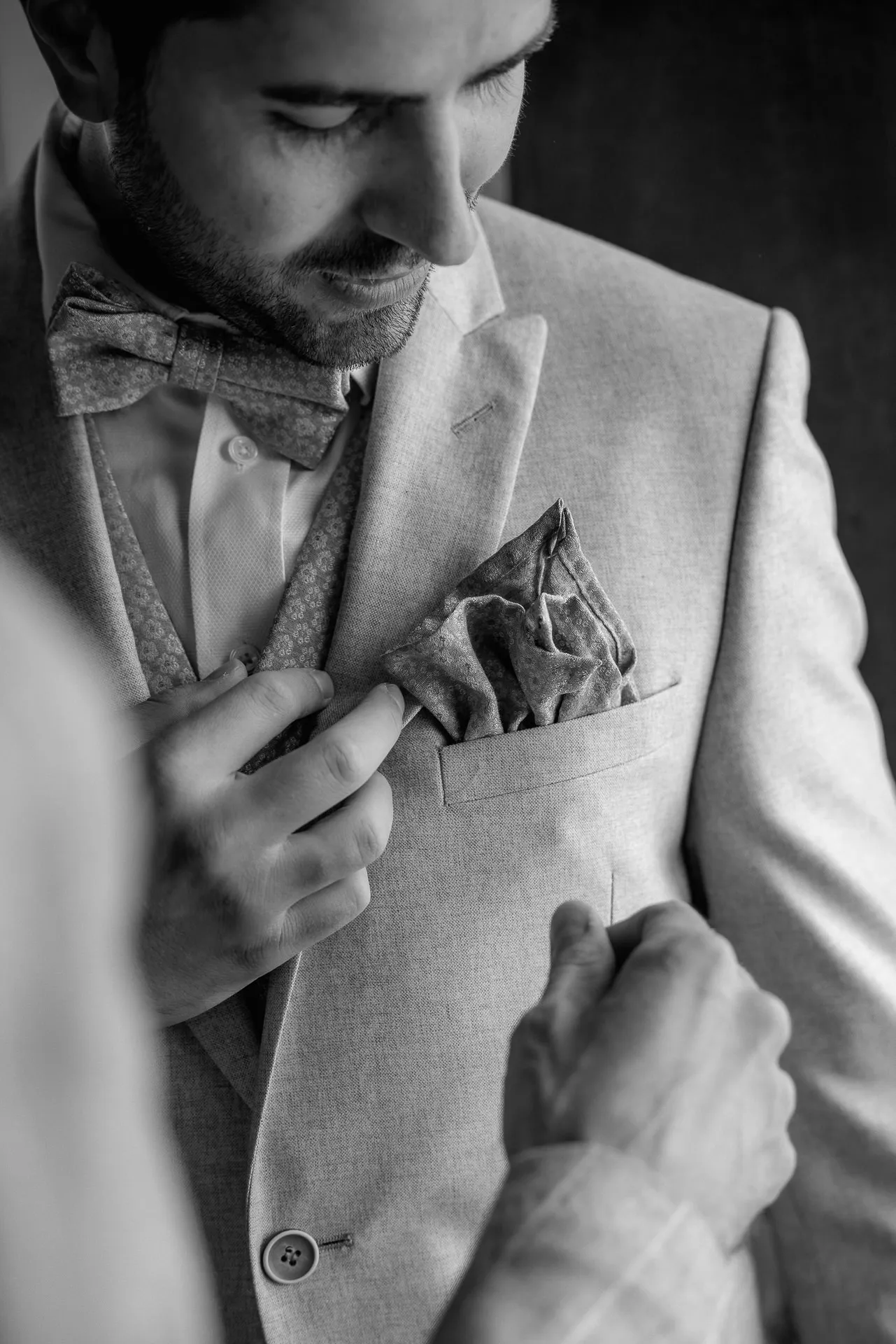 Detail of groom putting pocket square in place on wedding morning