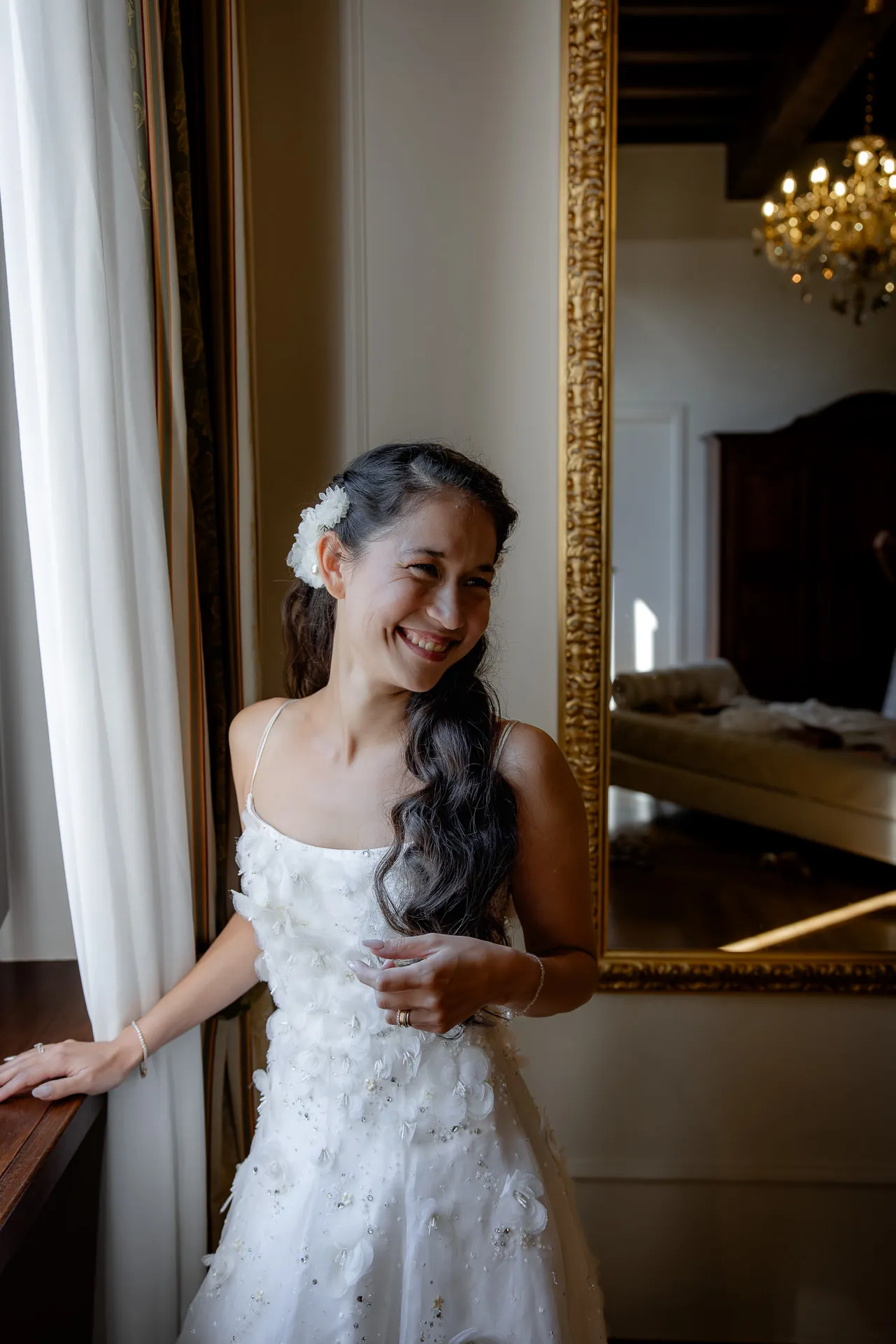 Radiant bride in white dress in front of golden mirror at Villa Cariola