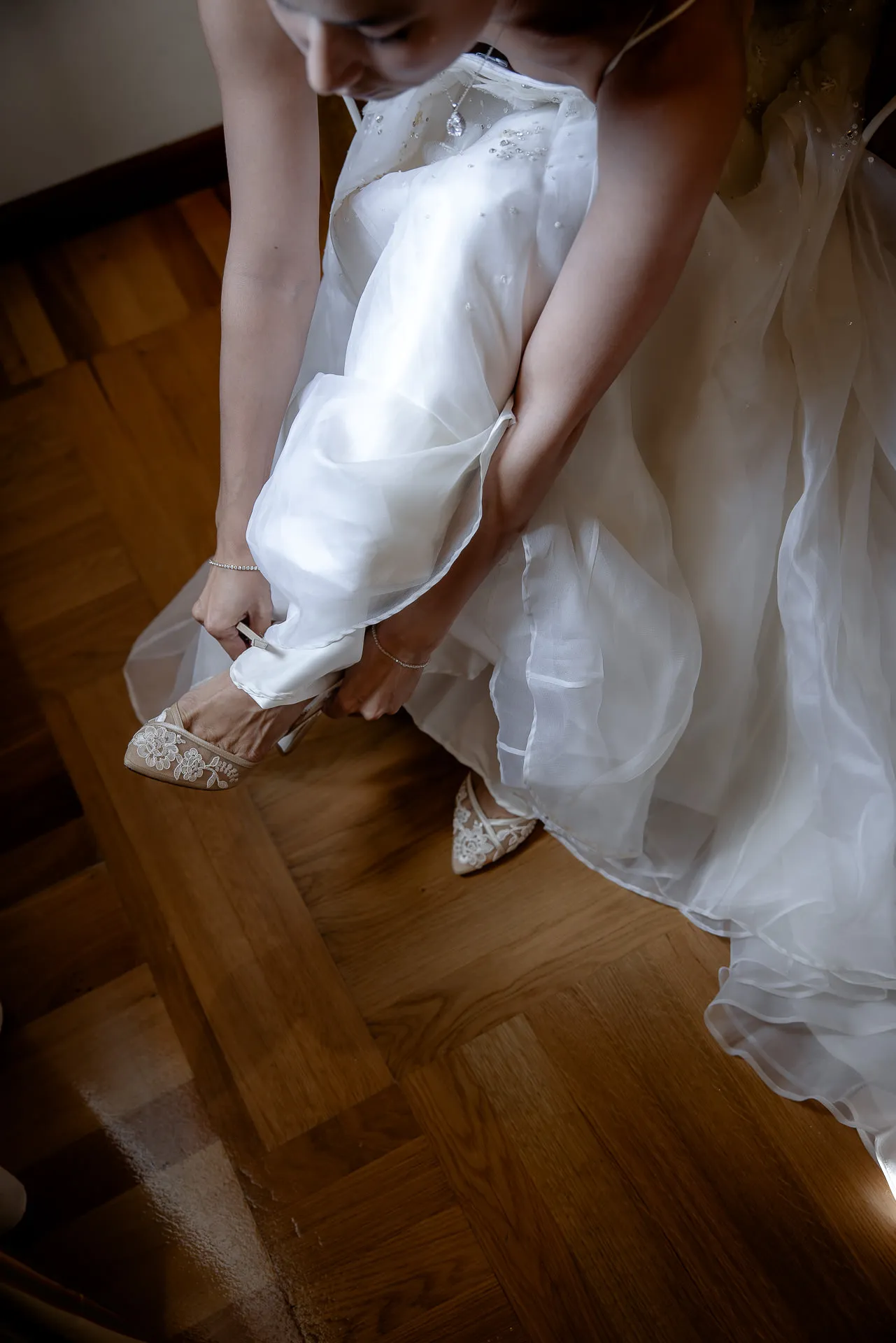 Bride putting on sparkling wedding shoes with flowing tulle dress
