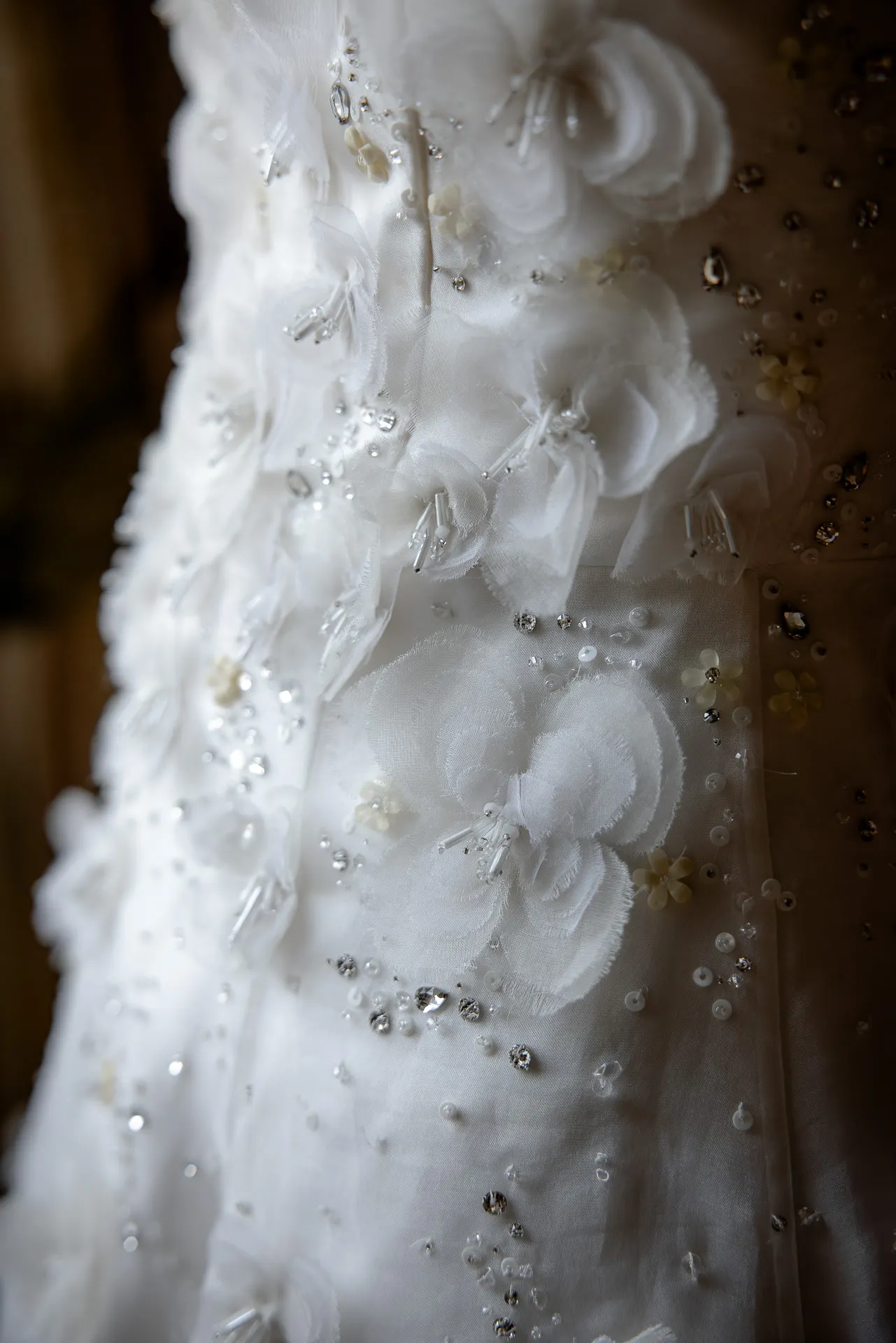 Detail shot of decorated wedding dress with pearls and fabric flowers