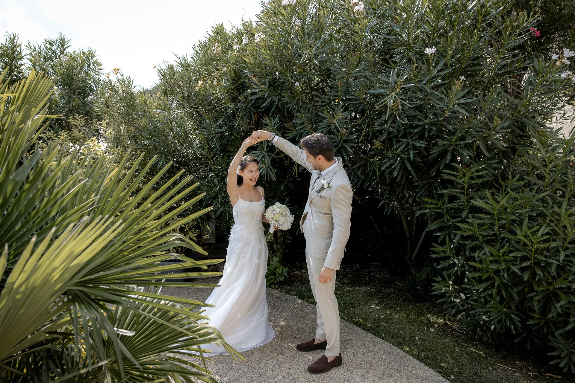 Wedding couple dancing between palm trees in Mediterranean garden at Lake Garda