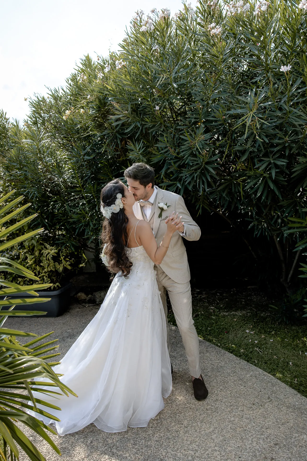 Intimate kiss of wedding couple between Mediterranean vegetation at Lake Garda