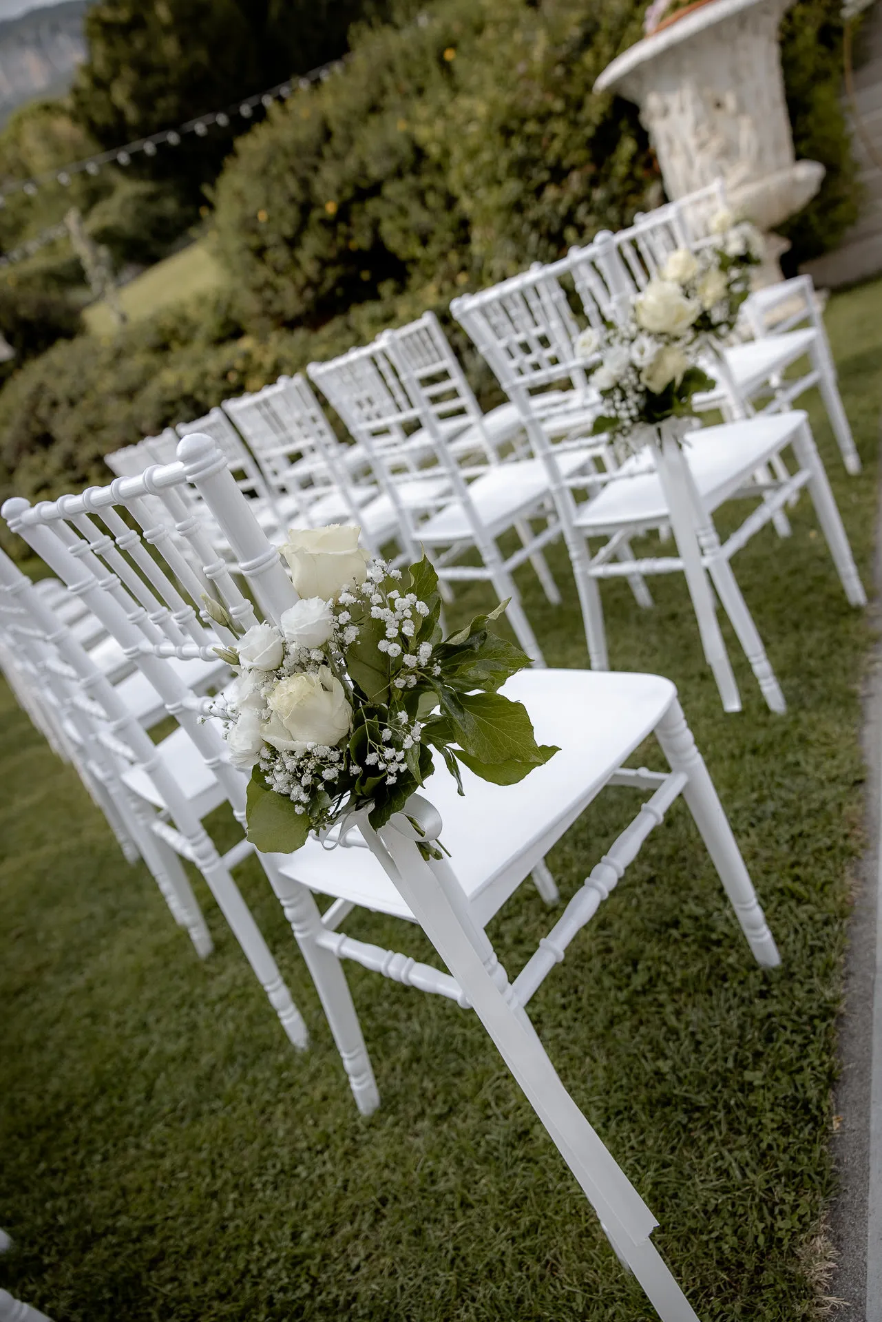 White chairs with floral decoration for wedding ceremony at Villa Cariola