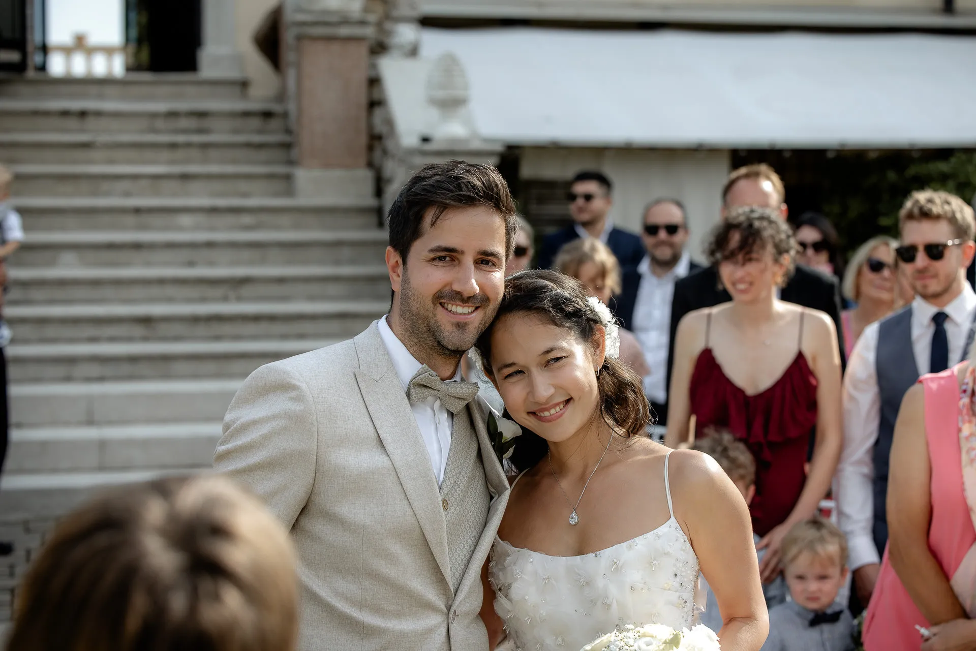 Beaming wedding couple after ceremony with guests in background