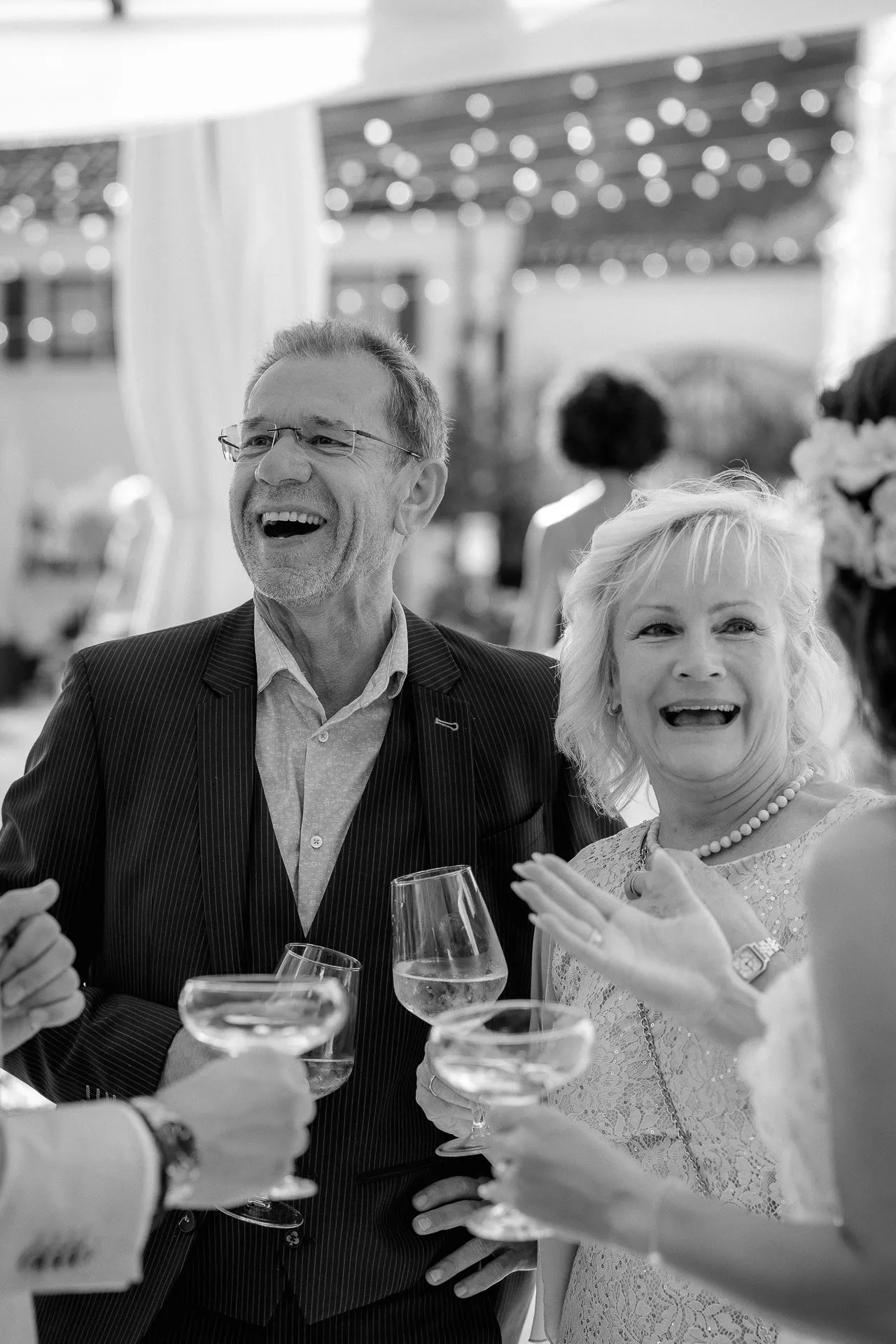 Laughing wedding guests toasting with wine glasses at celebration
