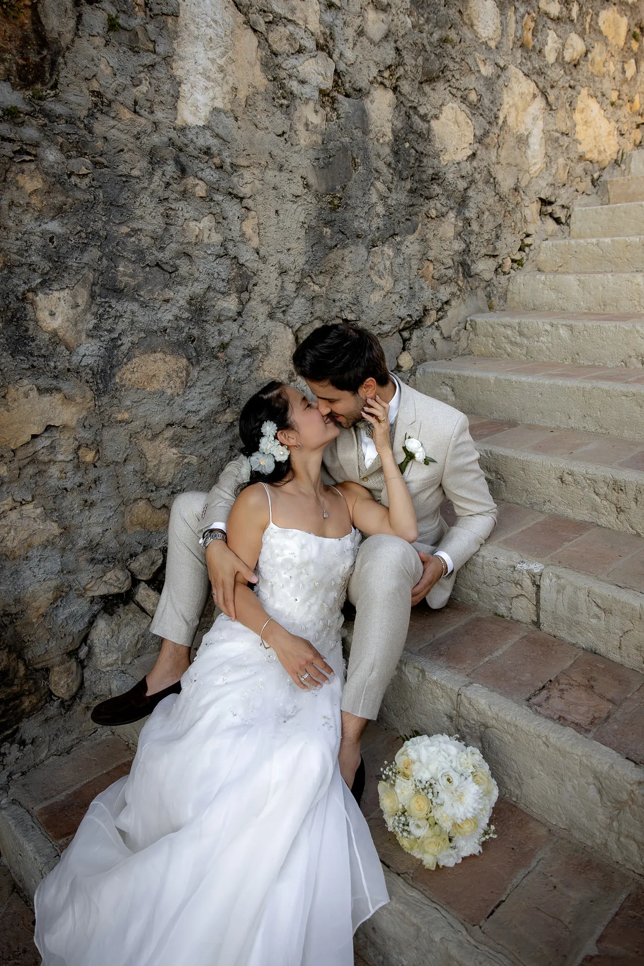 Romantic wedding couple sitting on historic stone staircase at Villa Cariola