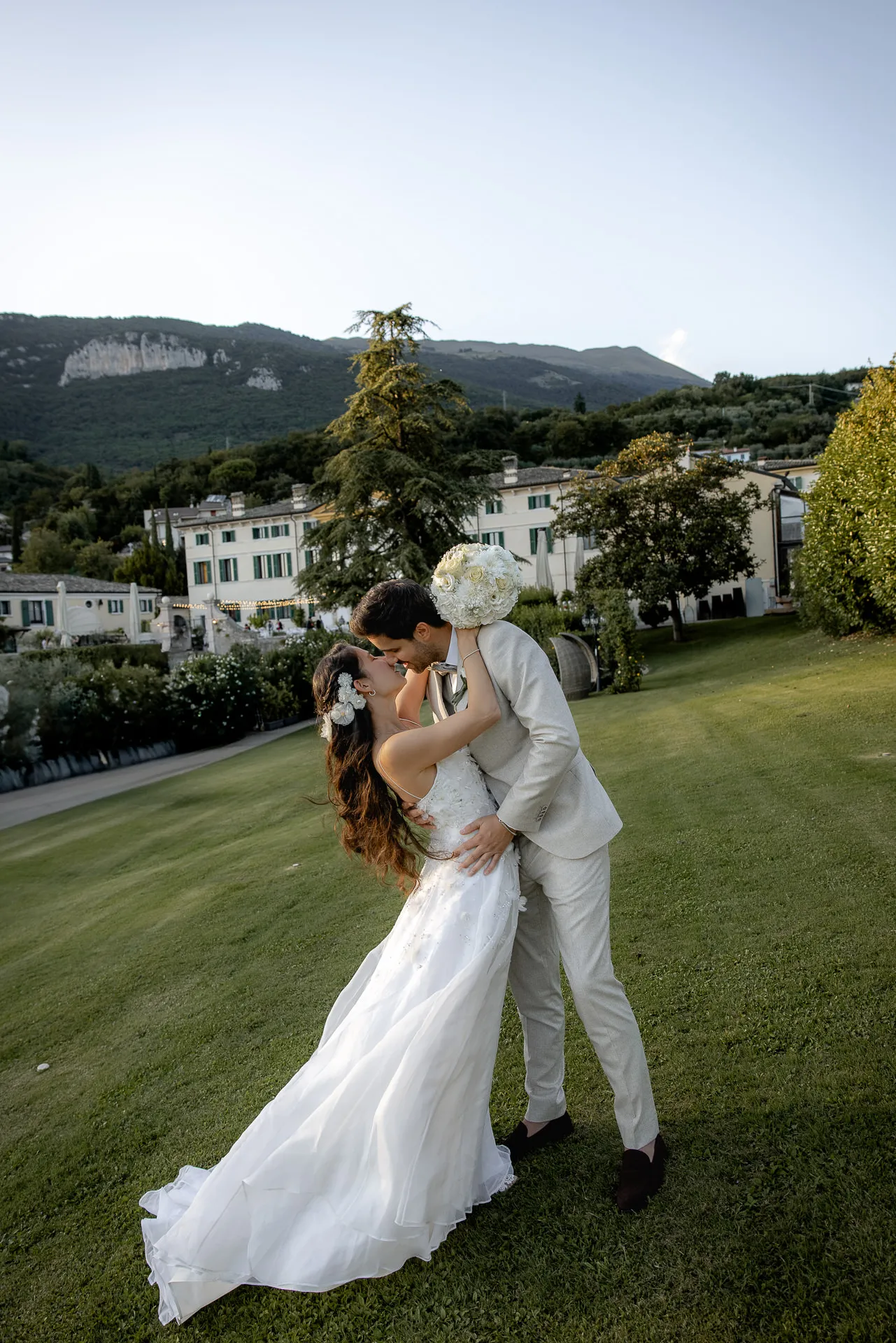 Romantic kiss of wedding couple in front of Villa Cariola with mountain panorama at Lake Garda