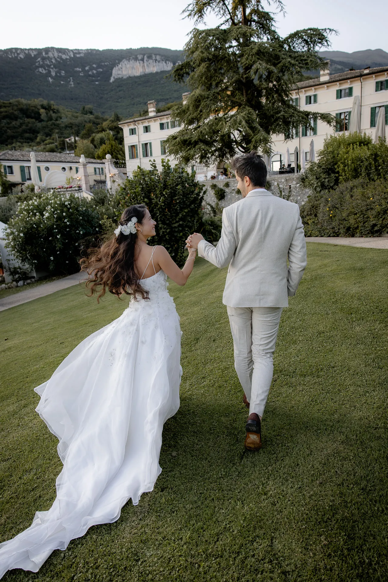 Wedding couple hand in hand in front of magnificent Villa Cariola with dramatic sky
