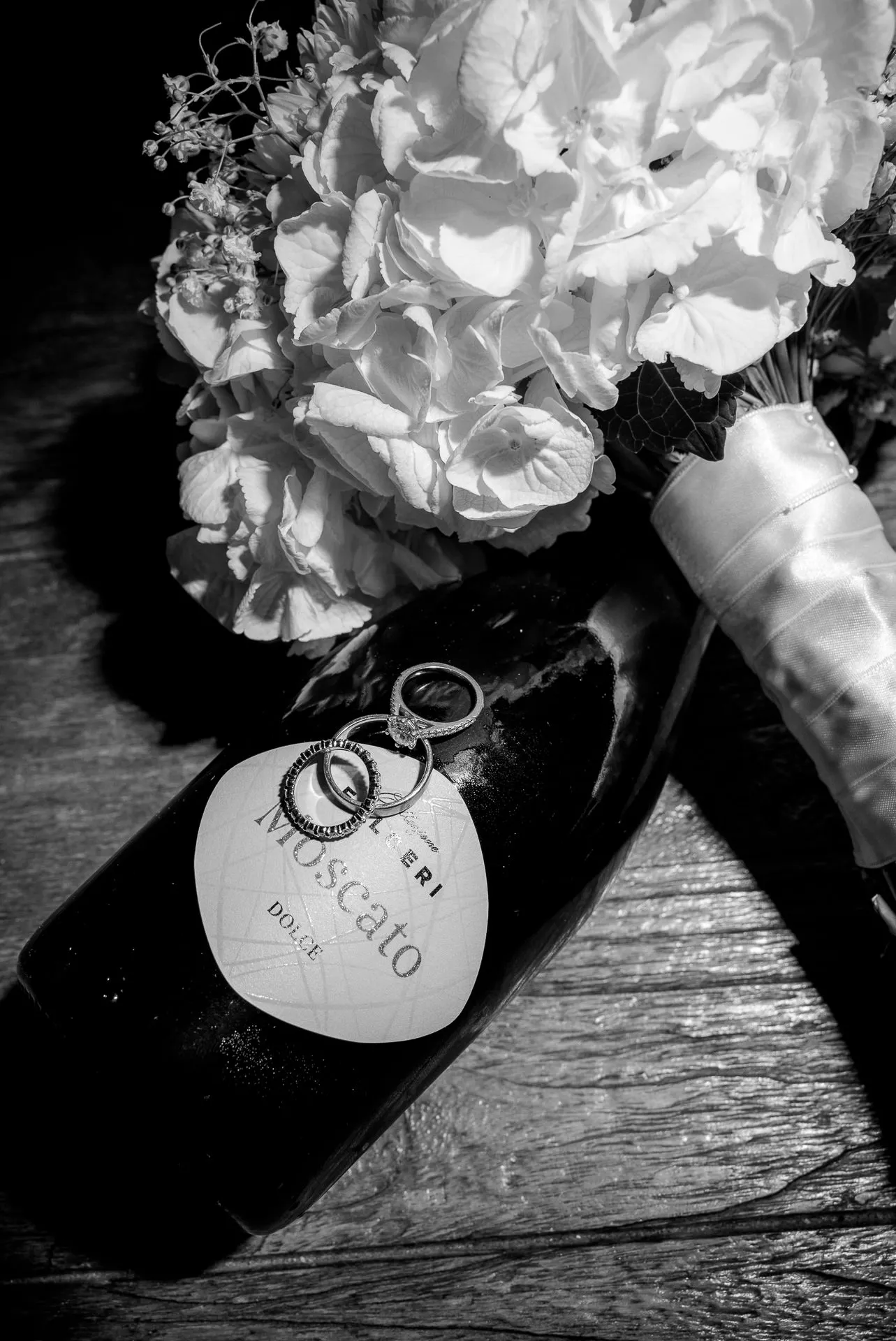Detail shot bridal bouquet and wedding rings on Moscato bottle at Italian wedding